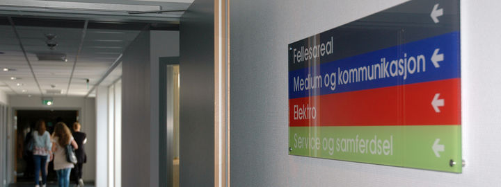 Gang med skilt til fellesareal, medium og kommunikasjon, elektro og service og samferdsel.