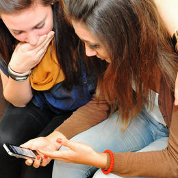 Bilde av to unge jenter som ser på ein smarttelefon.