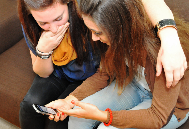 Foto: Pro Juventute ©cc-by Bilde av to unge jenter som ser på ein smarttelefon.