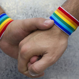 Bilete av to hender og regnbogefargar som illustrasjon på homofili.