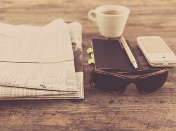 Hipster Office. Foto: Markus Spiske (flickr CC BY) avis, kaffekopp, notisblok, blyant, mobil og solbriller ligger på bordet