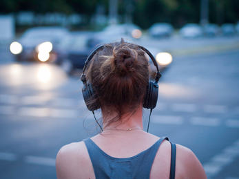 Woman with headphones. Foto: Sascha Kohlmann (flickr CC BY-SA) Kvinne med hodetelefon på vegkryss