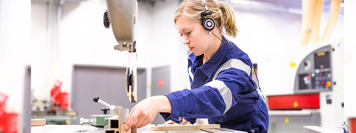 Elev i arbeid ved maskinene på treverkstad