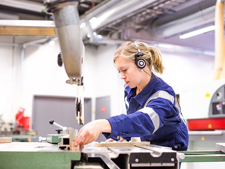 Elev i arbeid ved maskinene på treverkstad