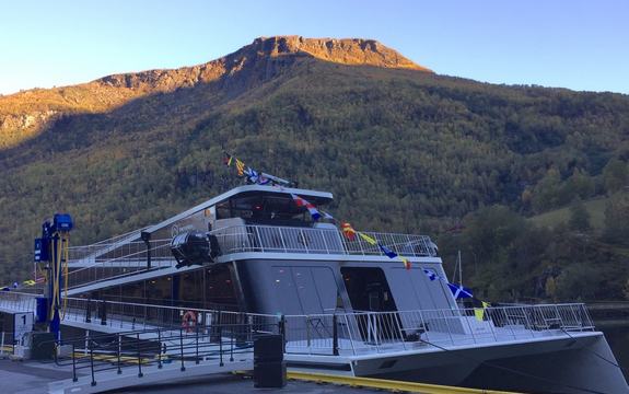 Moderne båt ved kai i ein fjord