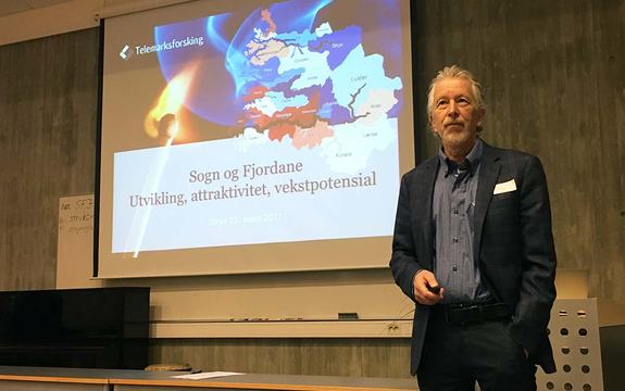Foto av forskar Knut Vareide  i Telemarksforsking som presenterer Regional analyse for Sogn og Fjordane 2016. Vareide står framfor power point-presentasjonen.
