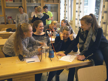 Foto som syner elevar i eit klasserom. Dei har apparat til naturfagseksperiment framføre seg på pulten.