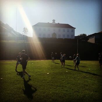 Bilde av skulen og elevar som spelar fotball.
