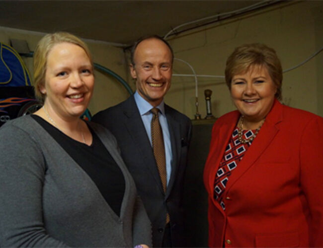 Statsminister Erna Solberg og administrerende direktør i Enova, Nils Kristian Nakstad lanserte Enovatilskuddet i hjemmet til Rikke Haugland Haavi. Etter å ha installert en luft-vann-varmepumpe kan Haavi kaste ut oljefyren fra garasjen. Foto: Enova