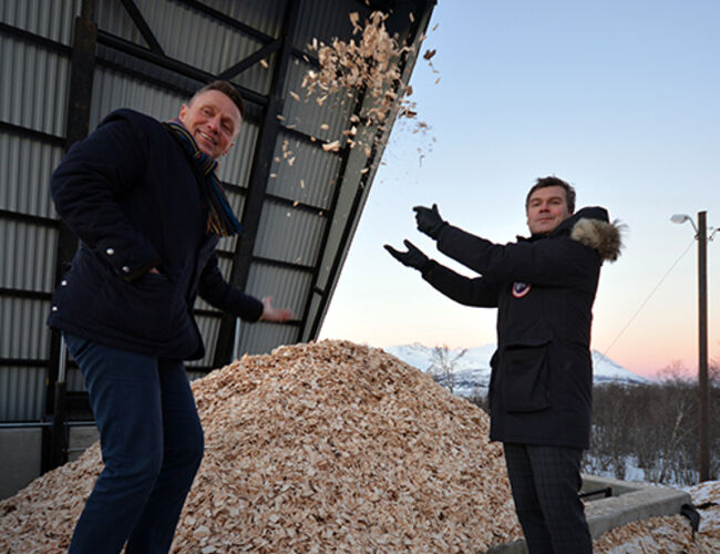 Geir Ove Ropphaugen (t.v.) fra Bioenergy AS og Jens Hugo Leiknes fra Forsvarsbygg nyter synet av miljøvennlig flis som har erstattet den gamle oljefyringen i Trondenes leir i Harstad. Foto: Terje Bartholsen, Forsvarsbygg