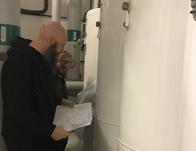Bjørn Ludvigsen og Harald Taxt Walnum fra SINTEF Byggforsk planlegger montering av måleutstyr i en varmesentral hos Boligbygg. Foto: Boligbygg