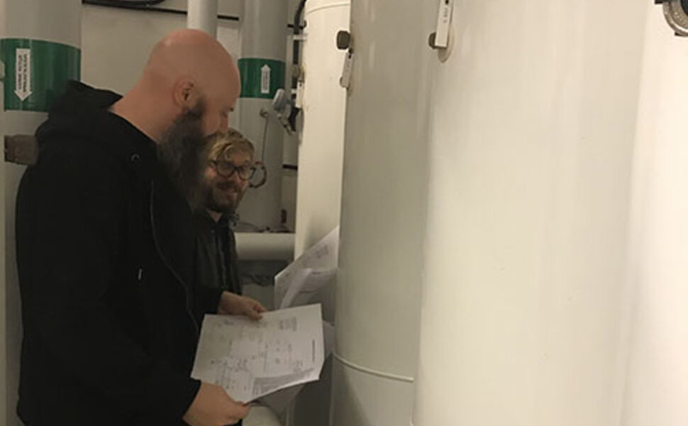 Bjørn Ludvigsen og Harald Taxt Walnum fra SINTEF Byggforsk planlegger montering av måleutstyr i en varmesentral hos Boligbygg. Foto: Boligbygg