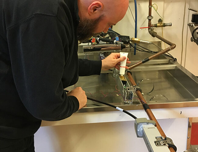 Bjørn Ludvigsen tester måleutstyr for bruk av varmtvann hos SINTEF Byggforsk. Utstyret vil nå plasseres i utvalgte bygg. Foto: Sintef