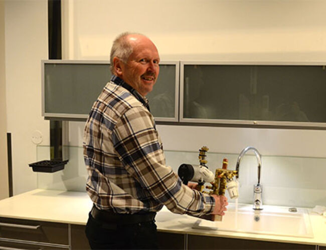 Enkel løsning. – Vi utnytter det varme tappevannet flere ganger, sier Rolf Julin, teknisk sjef i Agder Energi Varme. Her med pilotmodellen som har vært brukt under testing av det nye systemet. Foto: Agder Energi