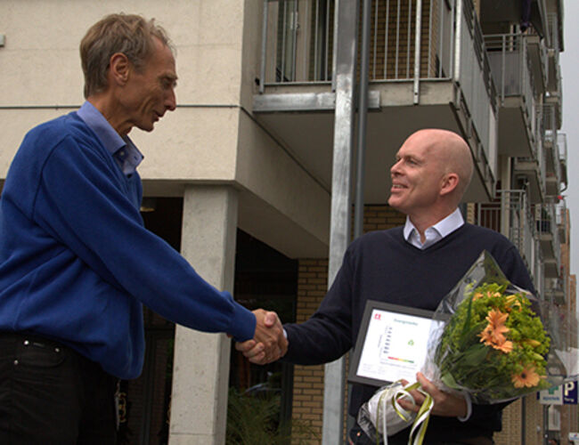 Jo Eigil Tveitane laget energiattest nummer 500 000 i NVEs energimerkesystem da leiligheten på Løren i Oslo ble lagt ut for salg, og fikk blomster og innrammet energiattest fra NVEs Olav Isachsen. Foto: NVE