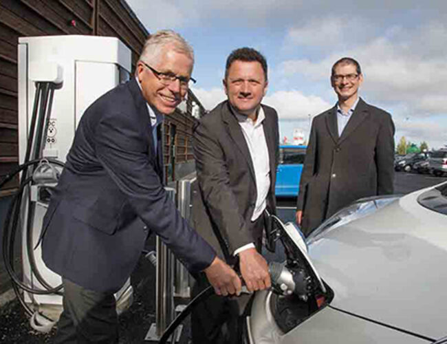 Kiwi-sjef Jan Paul Bjørkøy, General Manager i Zero Emission Strategy i Nissan Olivier Paturet og Manager for Zero Business Unit i Nissan Nicolas Bozek plugger inn den første elbilen. Foto: Kiwi