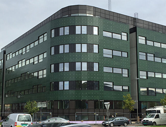 Bildet viser ”energibygget” til Union Eiendomsutvikling i Drammen, eller ”Solsmaragden” som det heter på folkemunne.  Alle de grønne feltene vi ser på fasaden, er solceller. Til sammen er det 1 242 m<sup>2</sup> med solceller på fasaden. Foto: Fusen AS