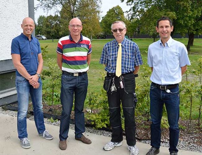 Fra venstre: Frank Olsen, Nordisk Energikontroll; Tor Sveine, Nordisk Energikontroll; vaktmester Kjell Hansen, Ramstad Skole og Ralph Sijstermans i Norconsult AS. På sletten i bakgrunnen er det borret 45 energibrønner. Foto: Tekniske Nyheter