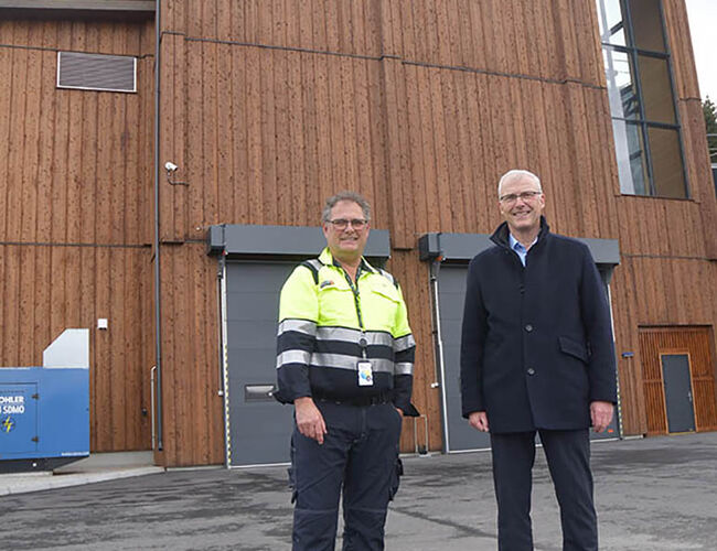 Driftsleder og prosjektleder Ove Heimnes og konsernsjef Øistein Andresen (t.h.) foran Norges første varmesentral bygget i heltre, og verdens første hvor en så stor del av bygget består av trevirke. Foto: Eidsiva