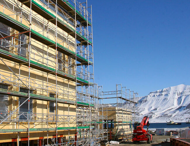 Den nye folkehøgskolen, som blir ført opp på Sjøskrenten i Longyearbyen,  bygges i massivtre med solcelleanlegg på taket. Foto: Ramirent