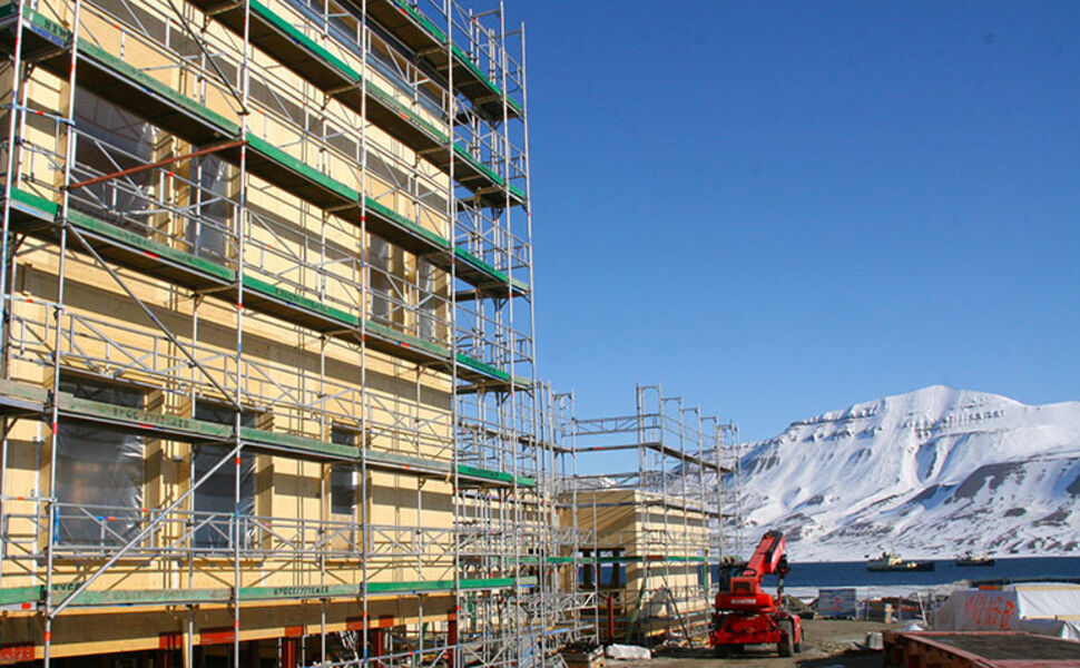 Den nye folkehøgskolen, som blir ført opp på Sjøskrenten i Longyearbyen,  bygges i massivtre med solcelleanlegg på taket. Foto: Ramirent