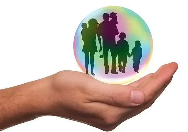 En hånd som holder en glasskule med en familie inni
