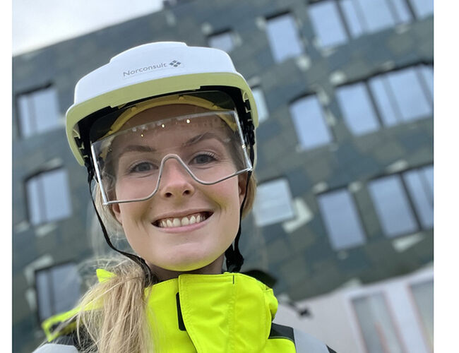 Mari Lauglo med solcelleanlegget på Voldsløkka skole i bakgrunnen. Foto: Norconsult