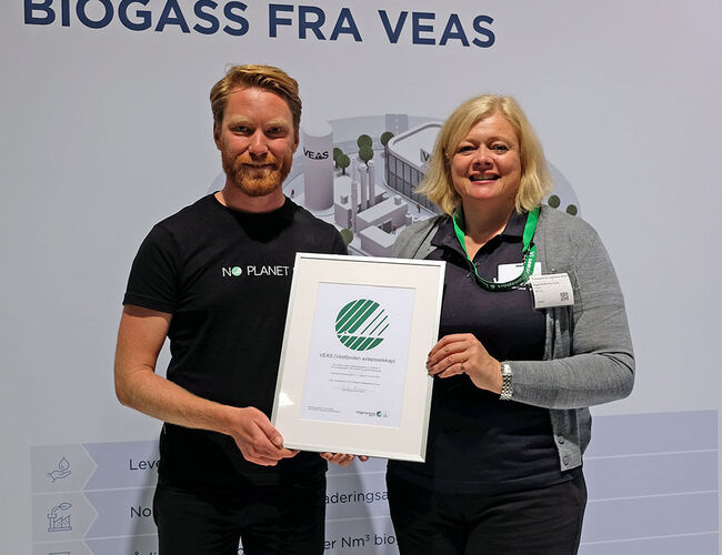 Bjørn Olav Aarø Strandli overrekker beviset for at VEAS har lisens på å produsere svanemerket biodrivstoff til Ragnhild Borchgrevink, administrerende direktør i VEAS. Foto: Miljømerking Norge