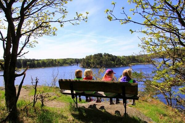 4 barn som sitter på en benk og ser utover et vann