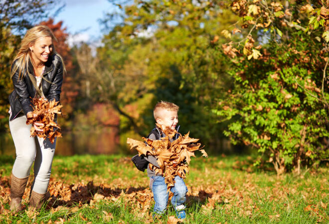 Dame og en liten gutt som leker med høstløv