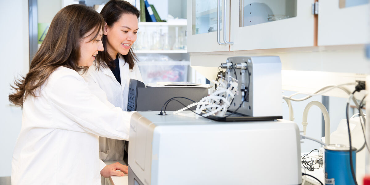 Two lab engineers in white coats working in the NIOM lab
