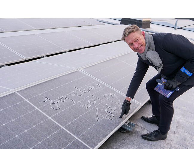 Energiminister Terje Aasland signerer et solcellepanel på taket av Alna Senter. Foto: Fanny Løvholm/Energidepartementet.