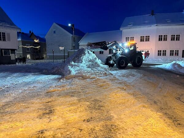 Brøytebil som skuffer snø i en stor snøhaug.