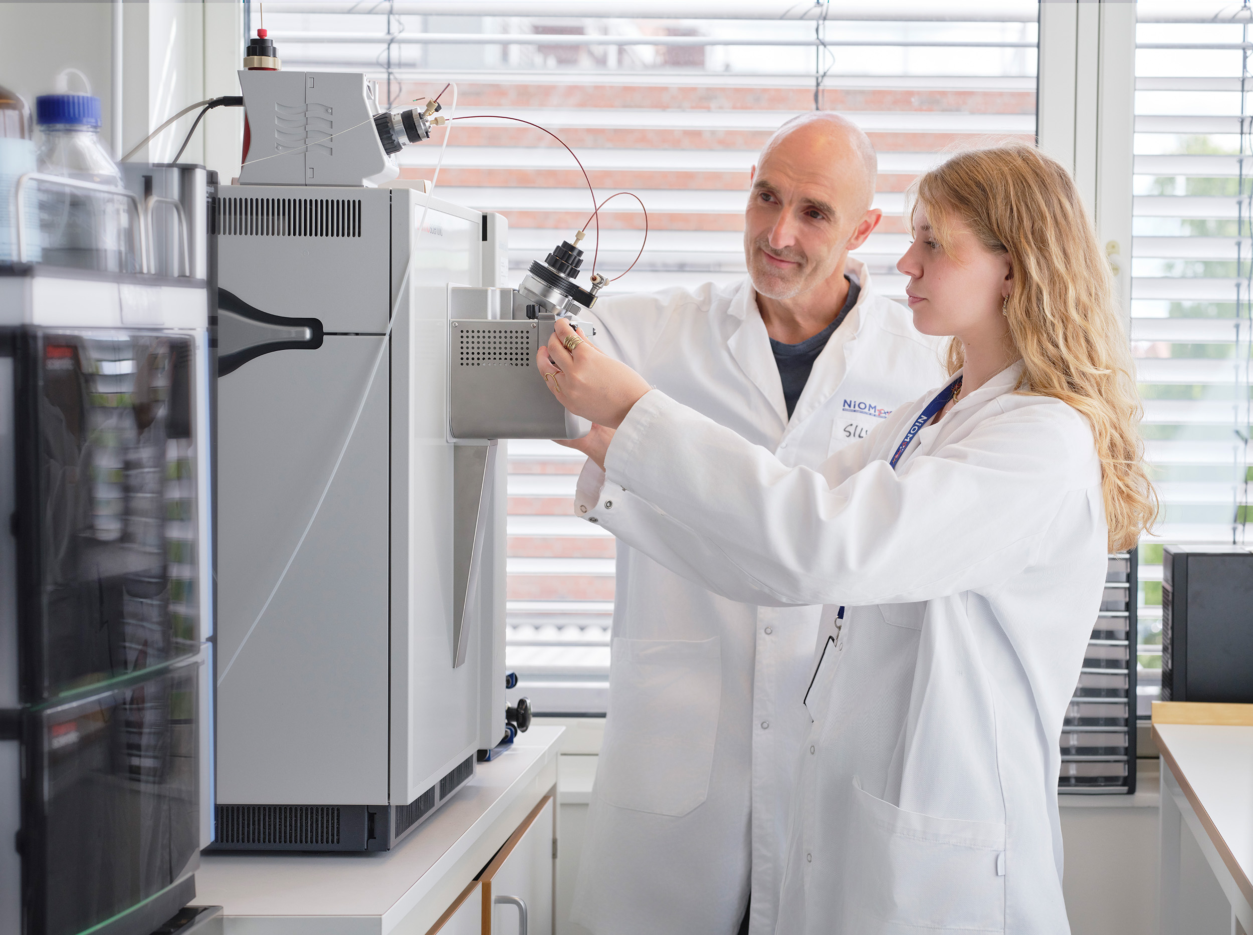Picture of two researchers at the High sensitivity analytical instrument (UHPLC-MS) at NIOM