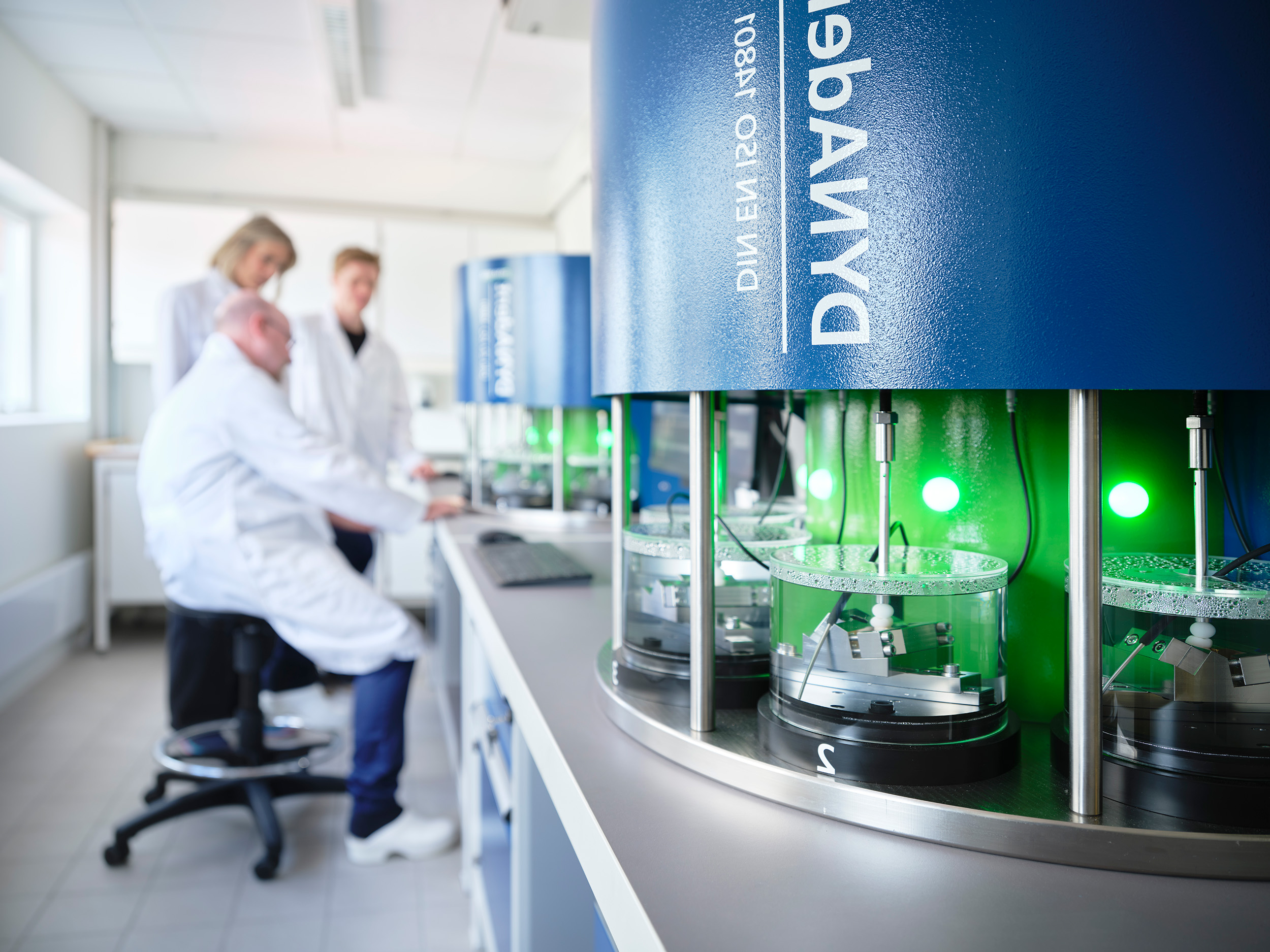 Picture of the DynaDENT instrument at NIOM with three researchers in the background