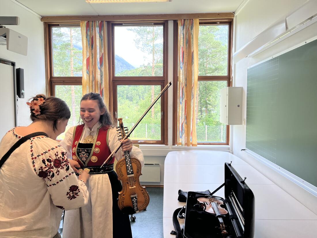 Ingrid Sofie Midtbø-Bruner får hjelpt til å rette opp bunaden av søster Hanna Moira før ho skal på scane for andre av sjette gong i dag.