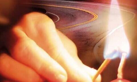 bilde av en hånd med en flammende fyrstikk, vei i bakgrunnen