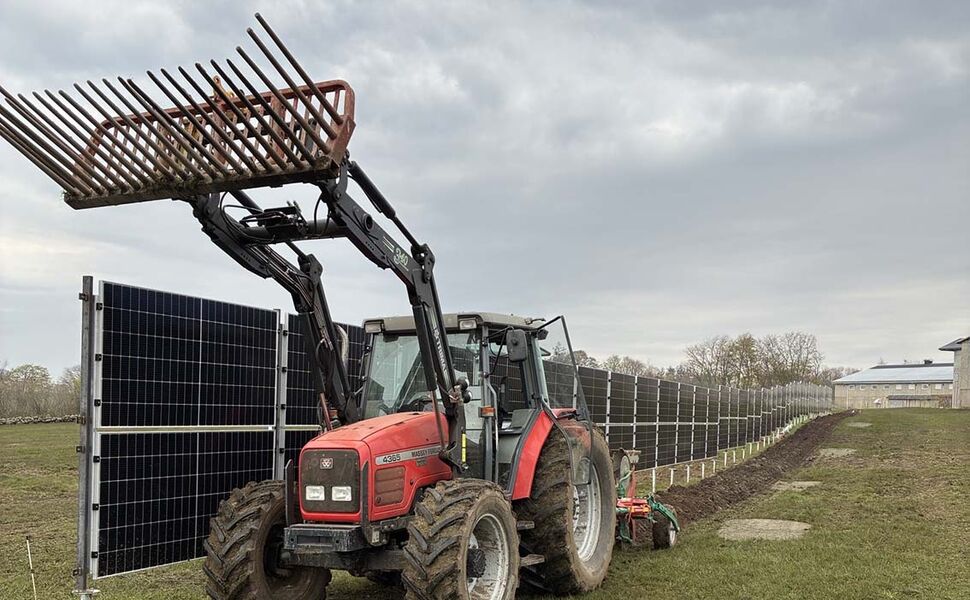 En traktor pløyer jorda tett inntil rekken med vertikale solcellepaneler. Foto: NIBIO En traktor pløyer jorda tett inntil rekken med vertikale solcellepaneler. Foto: NIBIO